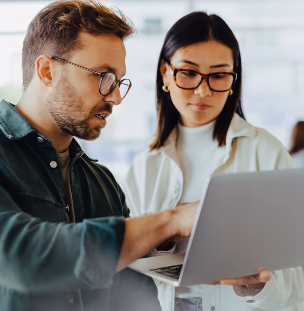 Two colleagues reviewing information together on a laptop in an office setting.