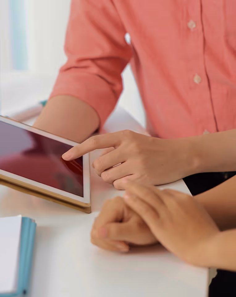 Close-up of two people interacting with a tablet device during a discussion.